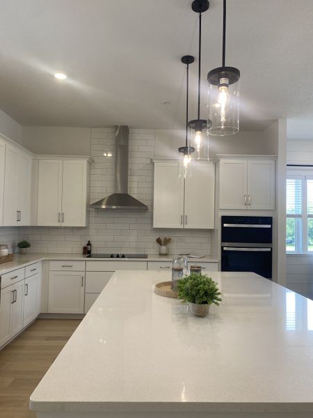 A modern kitchen with a large quartz island, pendant lighting, sleek white cabinetry, and stainless steel appliances. A modern kitchen with a large quartz island, pendant lighting, sleek white cabinetry, and stainless steel appliances.