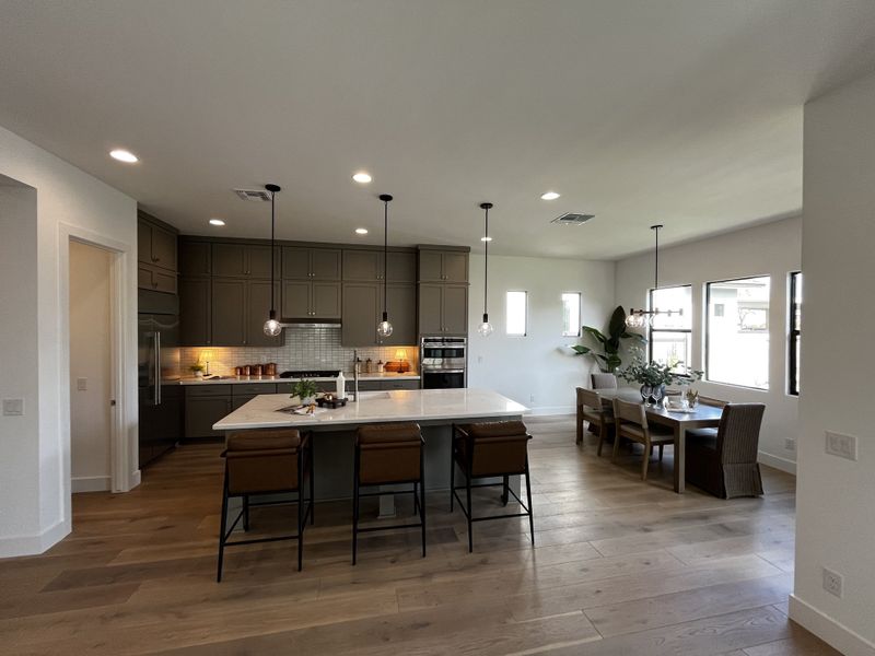 Modern open-concept kitchen and dining area with sleek cabinetry, pendant lighting, and a spacious island.