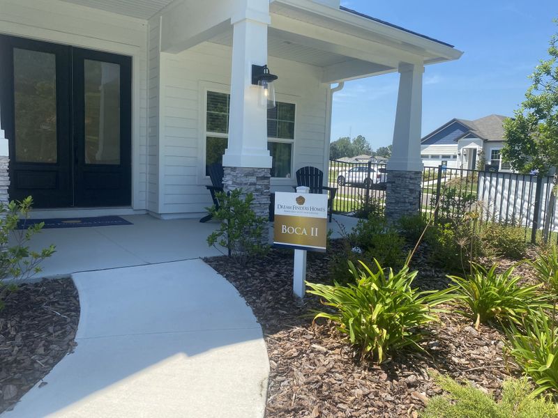 A charming white home with stone pillars and lush landscaping in Jennings Farm by Dream Finders Homes (Middleburg, FL).