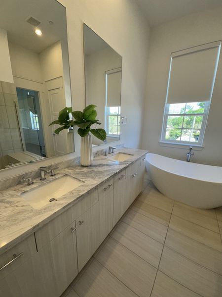 A luxurious bathroom featuring a marble double vanity, freestanding tub, and serene window view. A luxurious bathroom featuring a marble double vanity, freestanding tub, and serene window view.