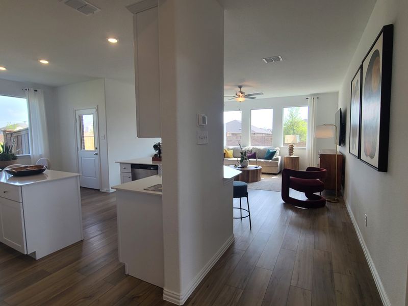 An open-concept living space with sleek wood floors, a bright kitchen island, and large windows inviting natural light. An open-concept living space with sleek wood floors, a bright kitchen island, and large windows inviting natural light.