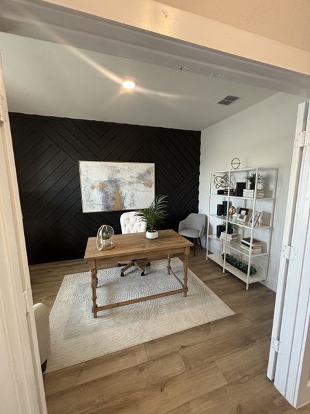 A sophisticated home office with a dark accent wall, wood flooring, and a classic desk setup for productivity. A sophisticated home office with a dark accent wall, wood flooring, and a classic desk setup for productivity.