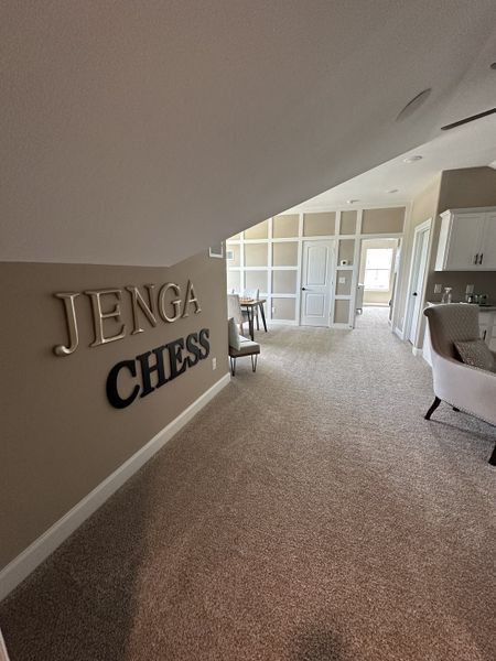 A cozy game room with carpeted floors, neutral walls, and decorative shelving. A cozy game room with carpeted floors, neutral walls, and decorative shelving.