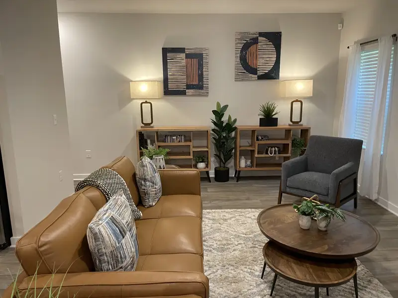 A cozy living room with a tan leather sofa, modern decor, and wooden accents, creating a warm and inviting atmosphere. A cozy living room with a tan leather sofa, modern decor, and wooden accents, creating a warm and inviting atmosphere.