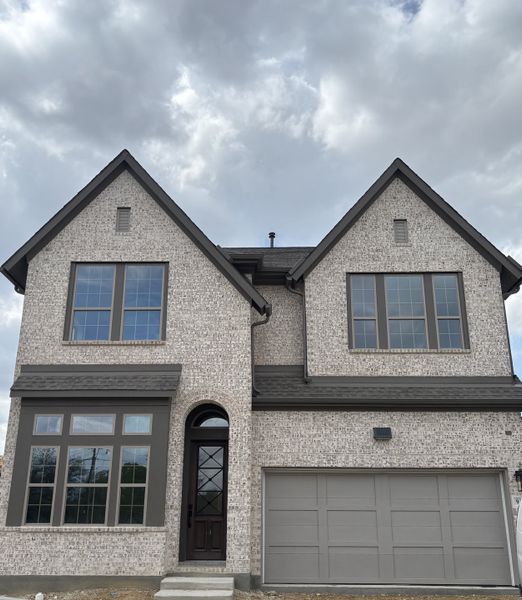 A charming gray-brick home with grand windows in Greenville Heights by David Weekley Homes (Dallas, TX).