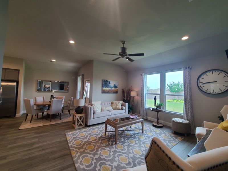 A cozy living-dining area with a ceiling fan, stylish rug, and large windows offering a garden view. A cozy living-dining area with a ceiling fan, stylish rug, and large windows offering a garden view.