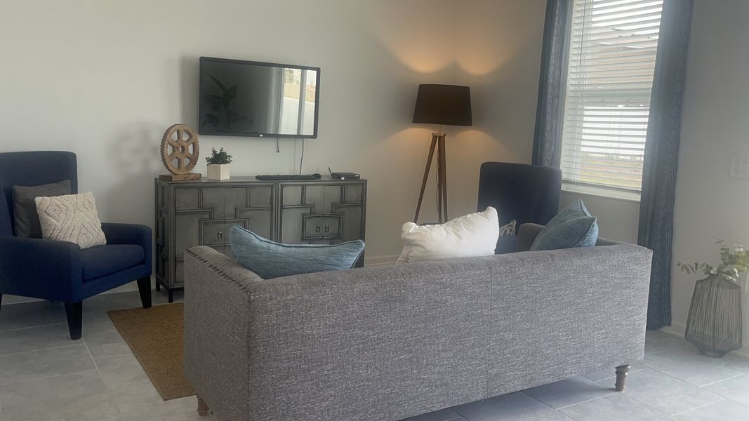 A cozy living room with a gray sofa, blue chairs, stylish decor, and soft lighting.