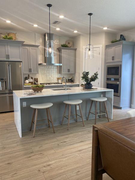 A modern kitchen featuring sleek gray cabinetry, an island with bar stools, and pendant lighting. A modern kitchen featuring sleek gray cabinetry, an island with bar stools, and pendant lighting.