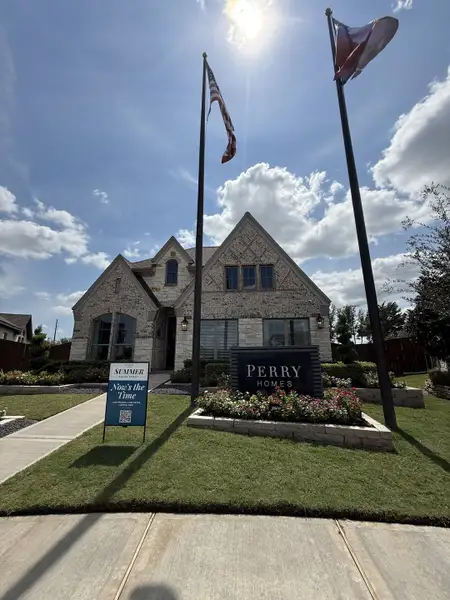 Elegant stone-brick home with lush landscaping in Meridiana 70' by Perry Homes (Manvel, TX).