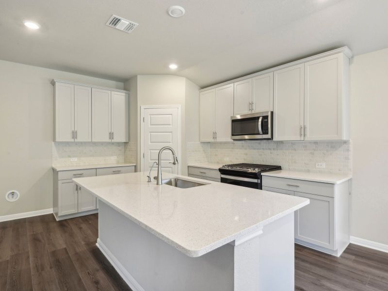 This beautiful kitchen features stone colored cabinets and quartz countertops.