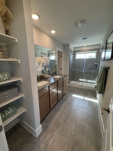 A modern bathroom featuring dual sinks, sleek cabinetry, and a spacious glass shower enclosure.