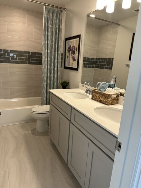 A modern bathroom with dual sinks, elegant gray cabinetry, and a stylish tiled tub/shower combo. A modern bathroom with dual sinks, elegant gray cabinetry, and a stylish tiled tub/shower combo.