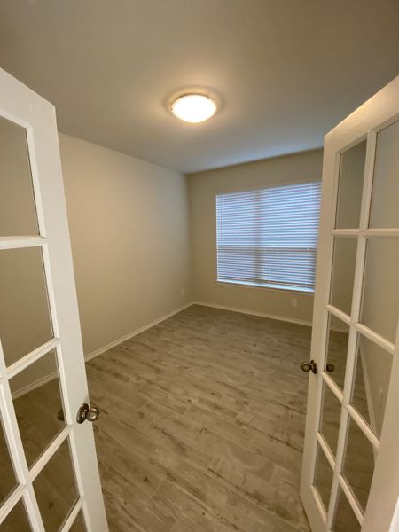 A cozy room with French doors, light wood flooring, and soft lighting.