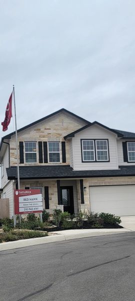 A charming two-story home with stone accents and a manicured front yard in Red Hawk Landing by CastleRock Communities (San Antonio, TX).