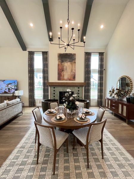 A sophisticated dining area with a round wood table, elegant chandelier, and cozy living space.