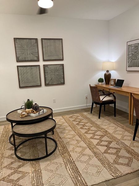 A modern home office with geometric wall art, cozy lighting, and a natural wood desk.