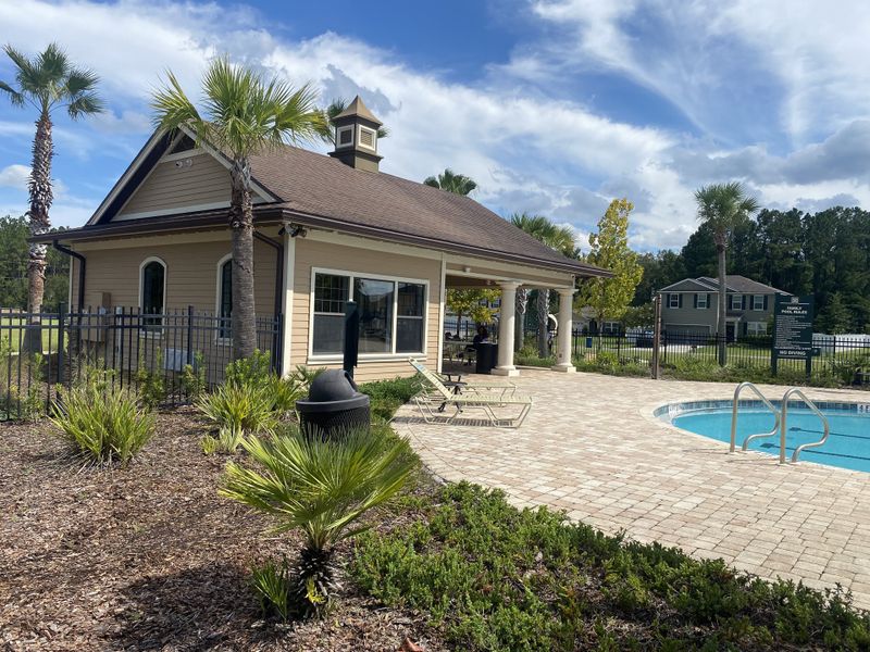 A cozy community pool with a charming clubhouse and tropical landscaping in Westport Landing by LGI Homes (Jacksonville, FL).