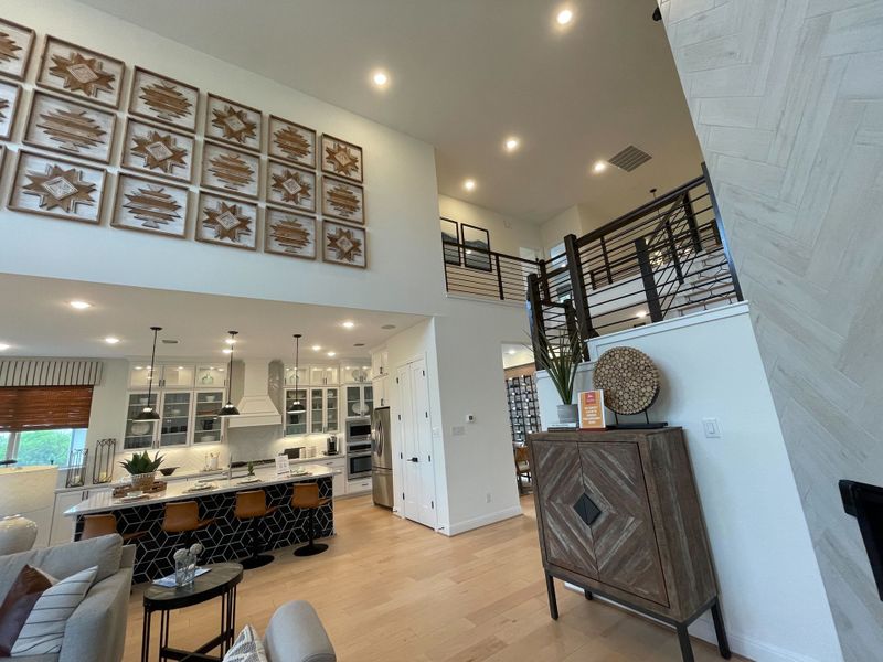 An open-concept living area with a high ceiling, modern kitchen island, stylish decor, and unique wall art. An open-concept living area with a high ceiling, modern kitchen island, stylish decor, and unique wall art.