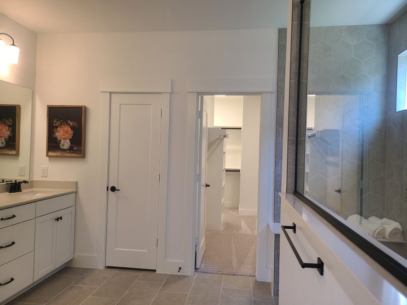 A modern bathroom with hexagonal tile, spacious vanity, and walk-in closet. Minimalist design with elegant fixtures. A modern bathroom with hexagonal tile, spacious vanity, and walk-in closet. Minimalist design with elegant fixtures.