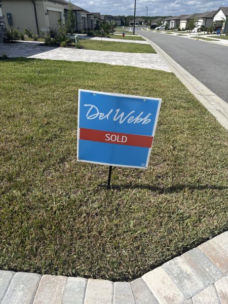 A picturesque street view in Del Webb Stone Creek by Del Webb, Ocala, FL, with homes and manicured lawns lined beautifully.