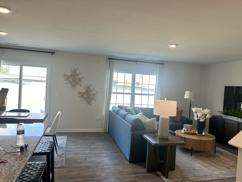 A cozy living room with a blue sectional, stylish decor, and natural light from large windows.
