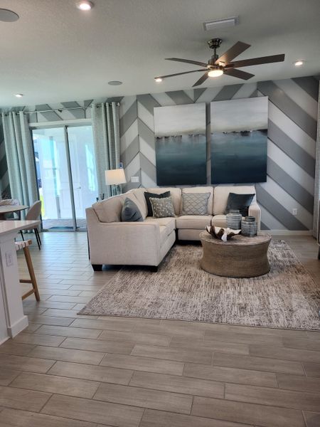 A cozy living room with a sectional sofa, abstract decor, chevron feature wall, and wood-tiled flooring.