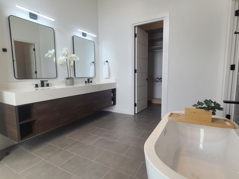 A contemporary bathroom featuring a sleek double vanity, elegant mirrors, and a luxurious tub with chic accents.