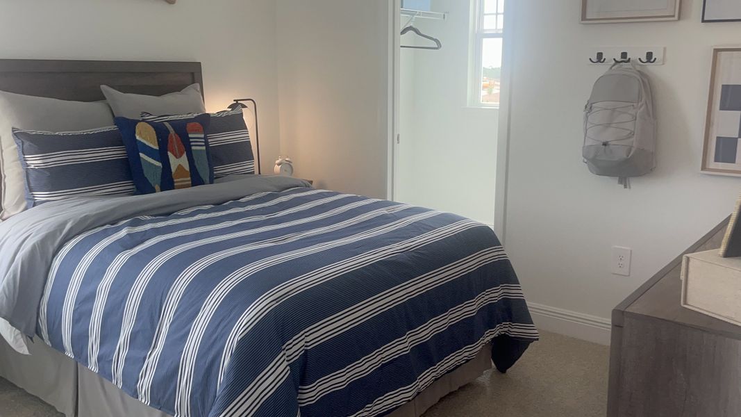 A cozy bedroom featuring a navy striped bedspread, soft lighting, and modern wall accents.