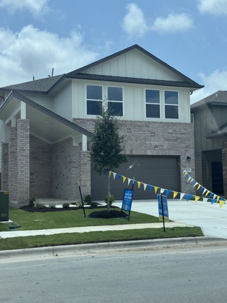 A modern brick home with clean lines and manicured lawn in Crosswinds by Milestone Community Builders (Kyle, TX).