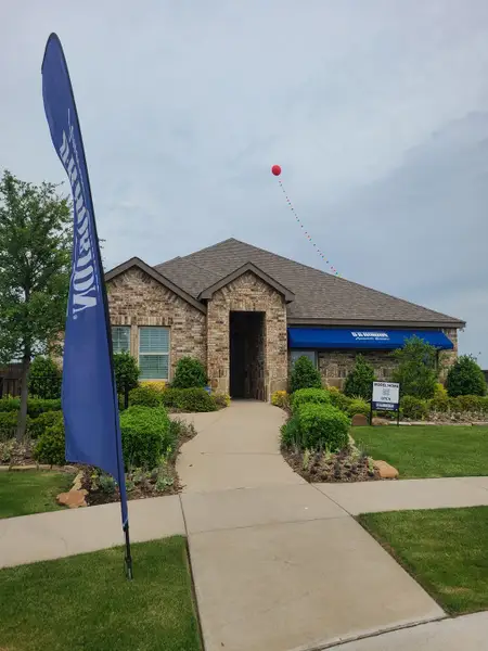 A charming brick home with a landscaped path and manicured shrubs in Winchester Crossing by D.R. Horton (Princeton, TX).