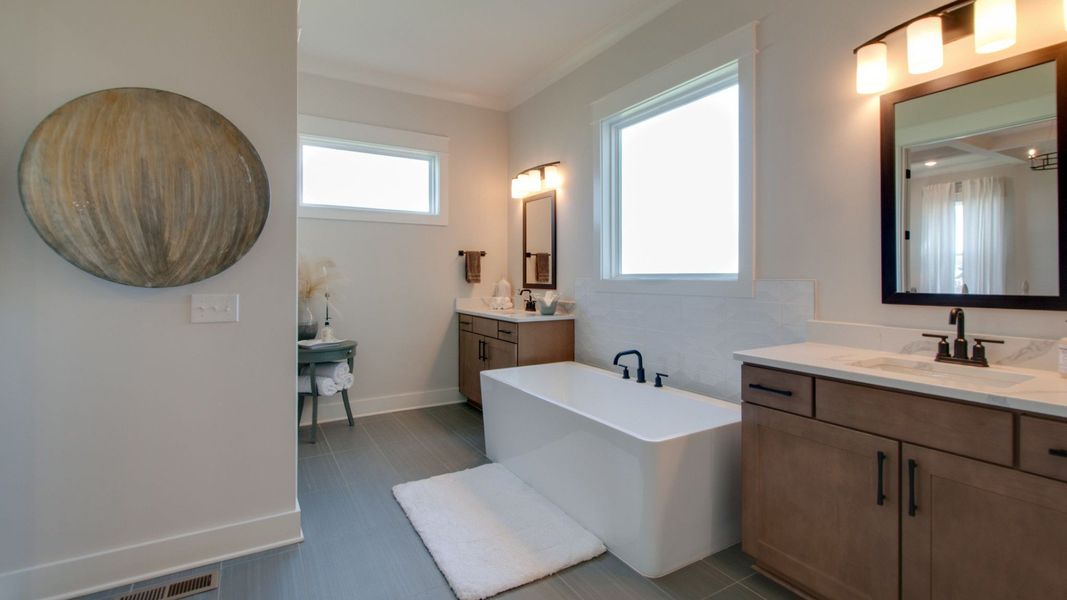Bathroom with double vanity, tub, and window Bathroom with double vanity, tub, and window