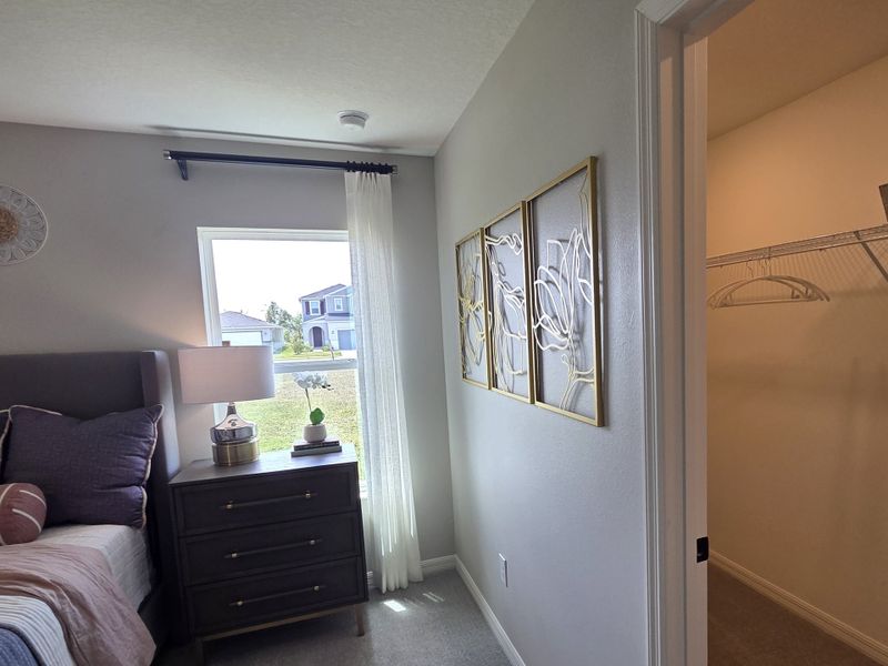 A cozy bedroom featuring elegant wall art, a nightstand with a lamp, and a walk-in closet for ample storage. A cozy bedroom featuring elegant wall art, a nightstand with a lamp, and a walk-in closet for ample storage.