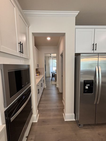 A modern kitchen with sleek stainless steel appliances, white cabinets, and warm wood flooring.