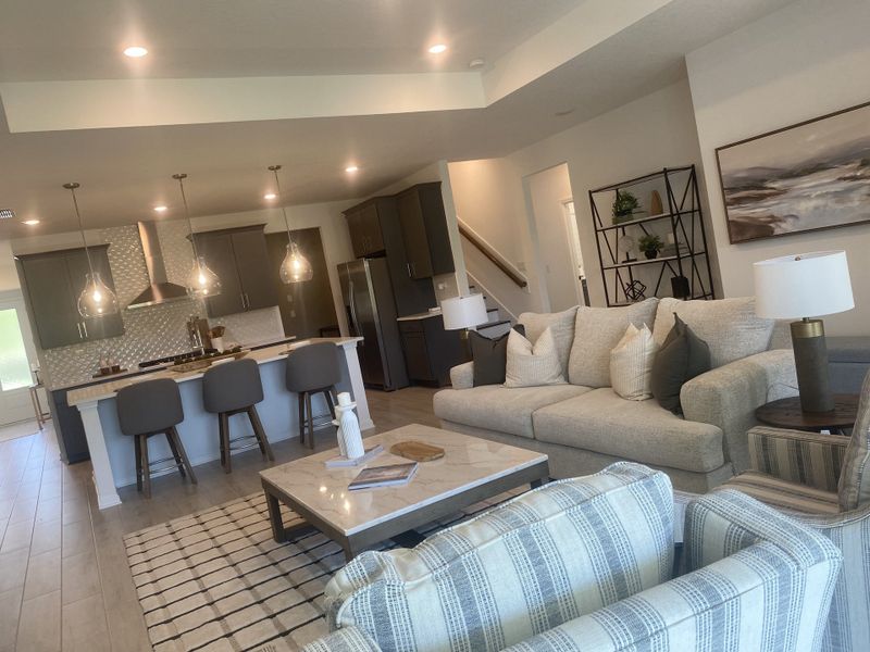 A modern open-concept living area featuring cozy seating, a sleek kitchen island, and ambient pendant lighting.