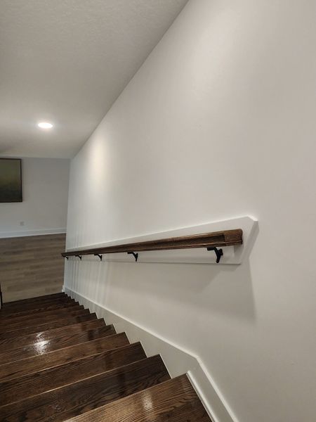 A sleek staircase with polished dark wood steps and a modern handrail, set against crisp white walls.