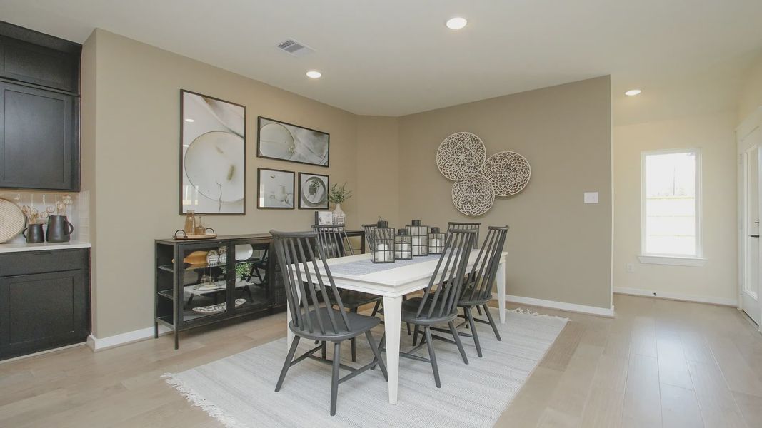 Luxurious dining room boasts stylish wall art and elegant hardwood flooring in Colony at Pinehurst.