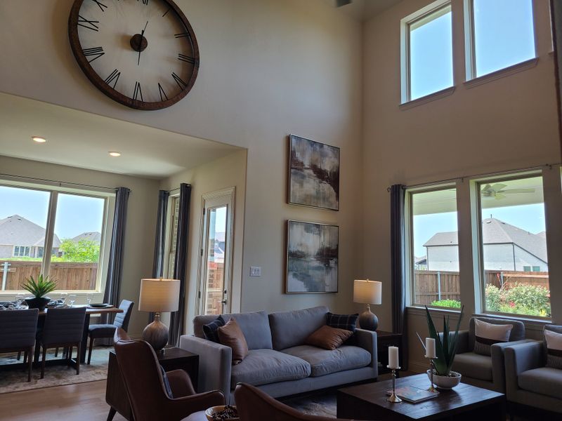 A spacious living area with high ceilings, large windows, a dining nook, and modern decor.