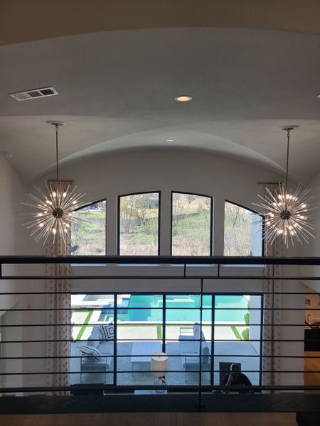 A luxurious interior view showcasing an open space with large windows, modern lighting, and a glimpse of a stunning pool outside.