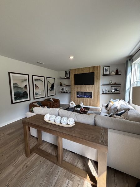 A cozy living room featuring a sectional sofa, textured wall with a TV, and elegant decor accents.