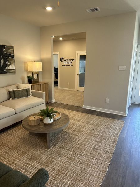 A cozy living room featuring a beige sofa, stylish round table, and textured rug, offering a warm and inviting atmosphere.