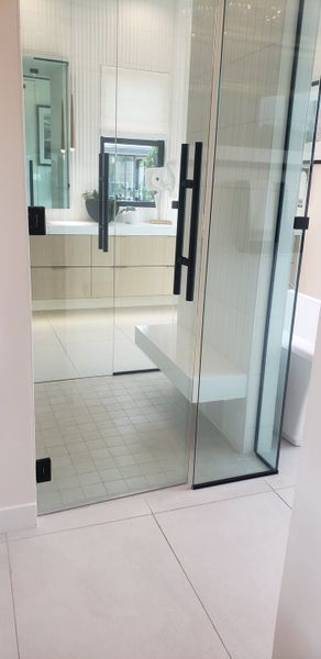 A contemporary bathroom with glass shower doors, sleek fixtures, and a light wood vanity.