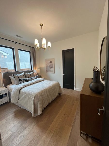 A cozy bedroom featuring a plush bed, elegant lighting, hardwood floors, and stylish decor. A cozy bedroom featuring a plush bed, elegant lighting, hardwood floors, and stylish decor.