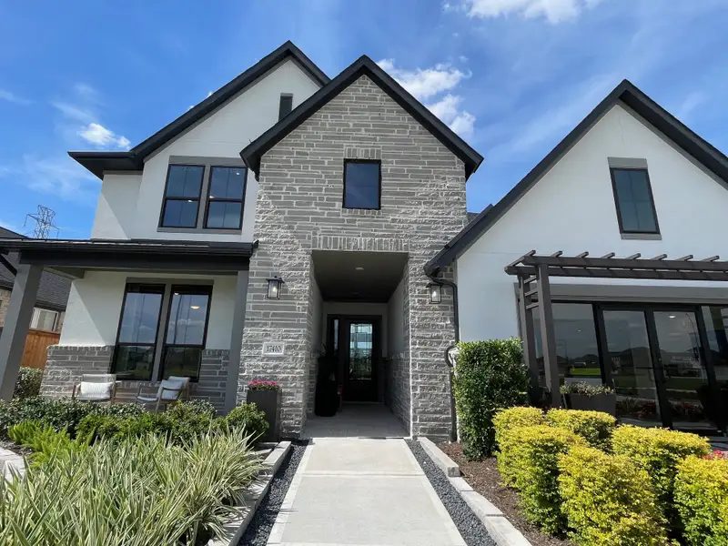 A modern gray-brick home with lush landscaping in Trillium 40′ by Tri Pointe Homes (Richmond, TX). A modern gray-brick home with lush landscaping in Trillium 40′ by Tri Pointe Homes (Richmond, TX).