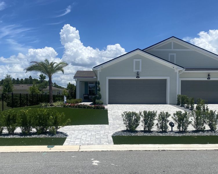A charming gray home with a manicured lawn and palm tree in RiverTown - WaterSong by Mattamy Homes (St. Johns, FL). A charming gray home with a manicured lawn and palm tree in RiverTown - WaterSong by Mattamy Homes (St. Johns, FL).