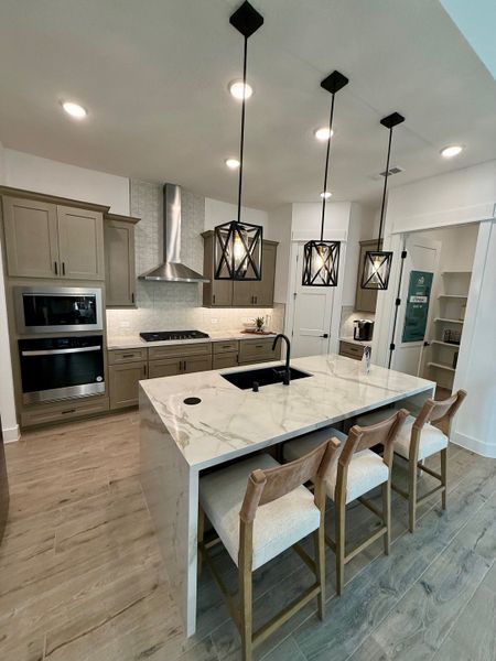 A contemporary kitchen with marble countertop, sleek cabinetry, pendant lights, and a functional central island.
