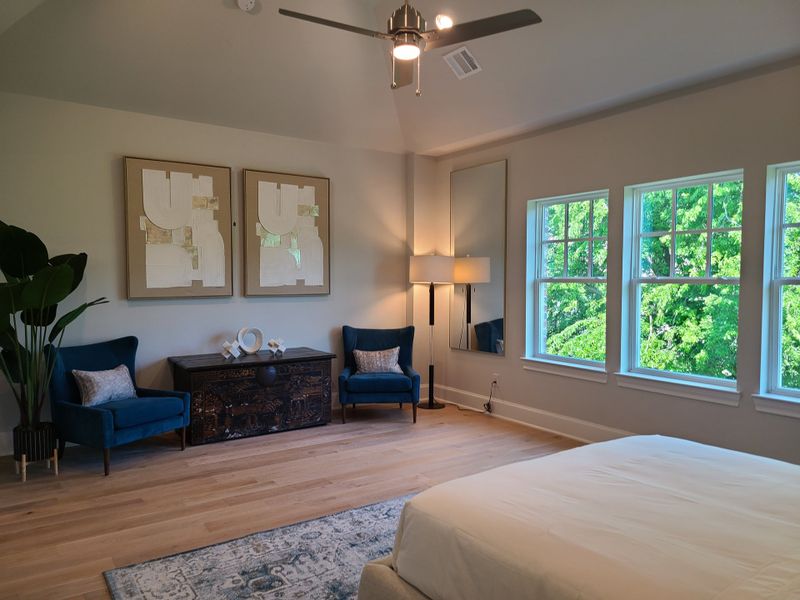 A serene bedroom with plush blue chairs, abstract art, and large windows offering lush views. A serene bedroom with plush blue chairs, abstract art, and large windows offering lush views.