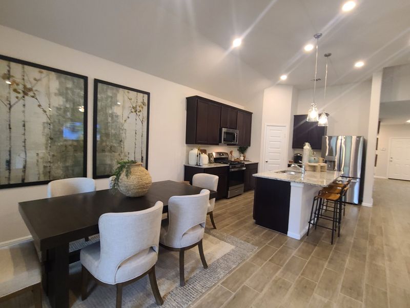 A modern kitchen and dining area with sleek cabinetry, pendant lighting, and elegant decor. A modern kitchen and dining area with sleek cabinetry, pendant lighting, and elegant decor.