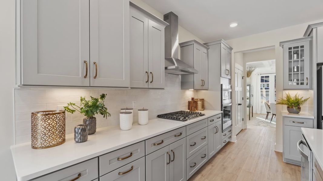 Modern kitchen with gold accents and light gray cabinetry giving a luxury feel at Woodglen by DRB Homes in Piedmont, SC