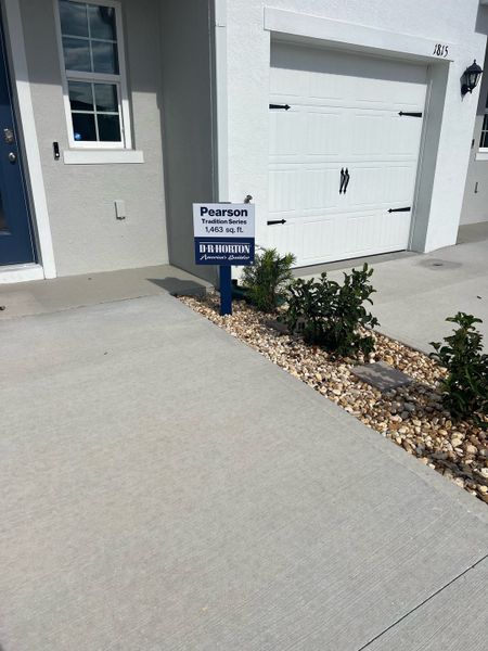 A charming modern home with a white exterior and elegant garage in Danbury at Ridgewood Lakes by D.R. Horton (Davenport, FL).