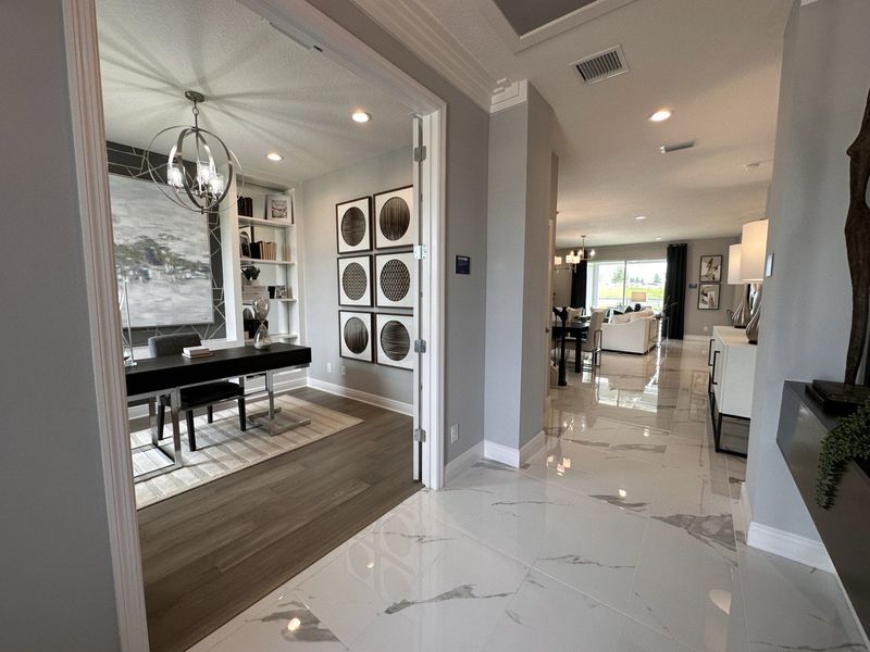 A contemporary home office with elegant decor, adjoining a sleek, open-plan living area with glossy tile floors and modern lighting.